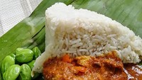 Nasi dagang biasanya dibungkus daun pisang bentuk kerucut seperti nasi uduk. Gulai ikan disiramkan dan bisa ditambah lalapan petai segar. Siapa takut? Foto : Instagram @dada_tastes