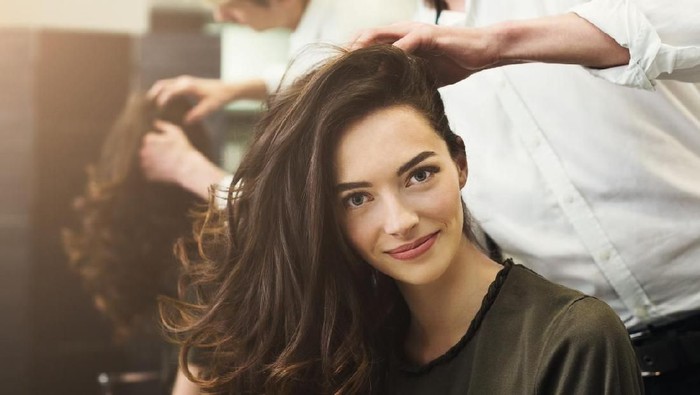1002144830 Happy woman sitting at beauty salon, making beautiful evening hairstyle with curls, copy space