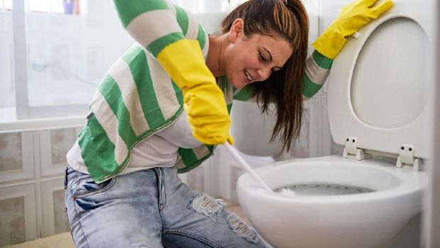 Ilustrasi membersihkan kamar mandi Shot of a young woman cleaning a bathroom toilet