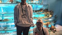 Mampir ke restoran seafood, dengan aneka live seafood di belakangnya, Zion.T berpose di balik lobster hingga kepiting bersama temannya. Foto: Instagram @ziont