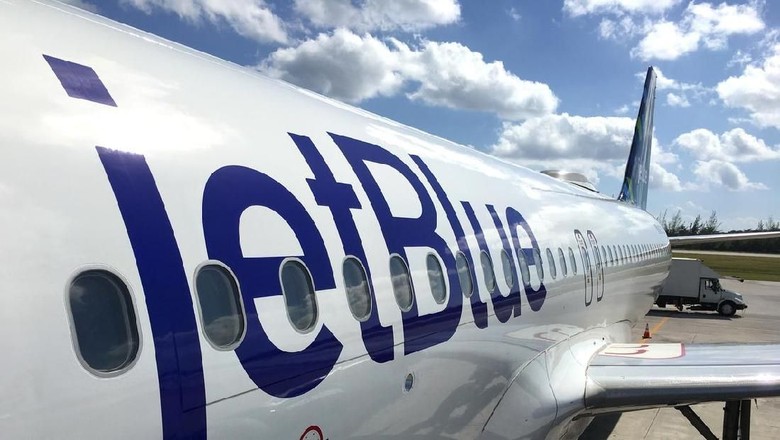 JetBlue, ILustrasi JetBlue George Town, Cayman Islands - December 21, 2017: Land operations and boarding in Owen Roberts Intl. Airport in Grand Cayman Islands. Close up of a JetBlue plane in a sunny day.