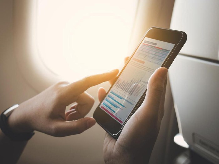 Businesswoman on plane using smartphone with graph on screen.Business technology and travel concepts ideas