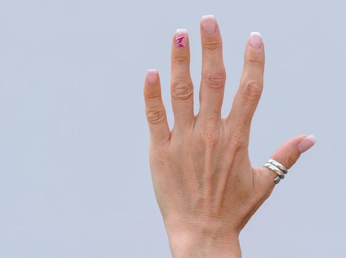 Close up of an antique gold ring with a large shiny blue gemstone on the soft woman hand placed in the water.