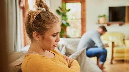 Young woman looking at bills while sitting on floor managing home budget