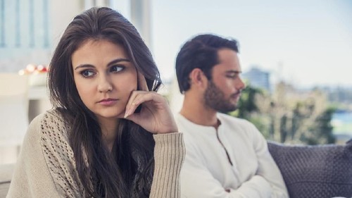 Young woman looking at bills while sitting on floor managing home budget