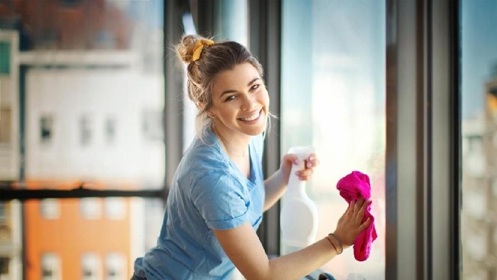 Woman with jug of vinegar and cleaning supplies at table