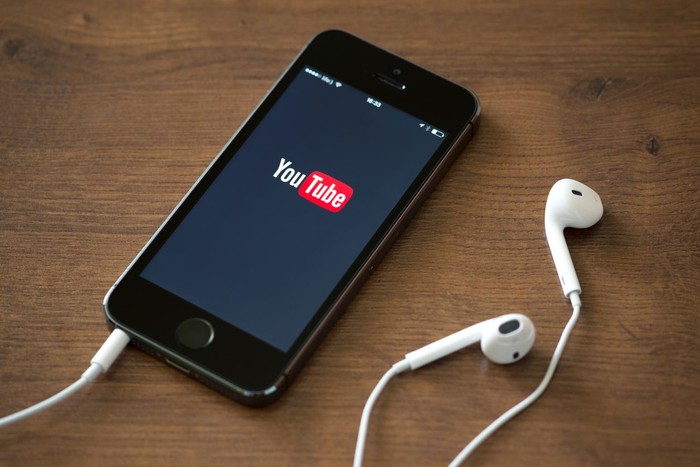 Kiev, Ukraine - June 5, 2014: Brand new Apple iPhone 5S with YouTube application service on the screen lying on a desk with headphones. YouTube is the worlds most popular online video-sharing website that founded in February 14, 2005