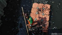 Petugas UPK Badan Air Dinas Lingkungan Hidup DKI Jakarta menyusuri sungai untuk mengangkut sampah.