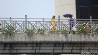 Tiadanya tutup JPO membuat pengguna JPO harus lebih cerdik untuk menyiasati panasnya terik matahari di siang hari. Payung adalah salah satu solusinya (Randy/detikcom)