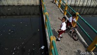 Dua anak asyik bermain sepeda di jembatan Kali Item.