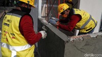 Dua pekerja tengah membangun tembok.