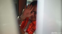 Dengan tangan diborgol, Alexius melambaikan tangan kepada wartawan.
