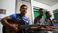 Seorang prajurit nampak memainkan gitar saat berbincang dengan sejumla prajurit lainnya di malam hari.