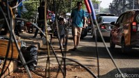 Kabel yang menjuntai itu membuat trotoar tidak berfungsi. Pejalan kaki pun terpaksa melintas di bahu jalan yang ramai oleh lalu-lalang kendaraan.