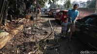 Warga melintas di samping kabel yang menjuntai ke jalanan di kawasan Kelapa Gading Kirana, Kamis (7/10/2019).