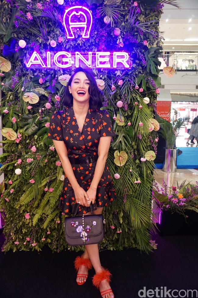 Ririn hadir dalam balutan shirtdress hitam bermotif strawberry yang playful dipadu sandal heels merah beraksen bulu. Tidak ketinggalan, tas Aigner seri Epona Bag Pansy berwarna hitam yang dipermanis dengan bordiran motif floral. (Foto: Daniel Ngantung/Wolipop)