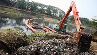 Petugas mengerahkan ekskavator untuk mengeruk sampah di Kanal Banjir Timur.