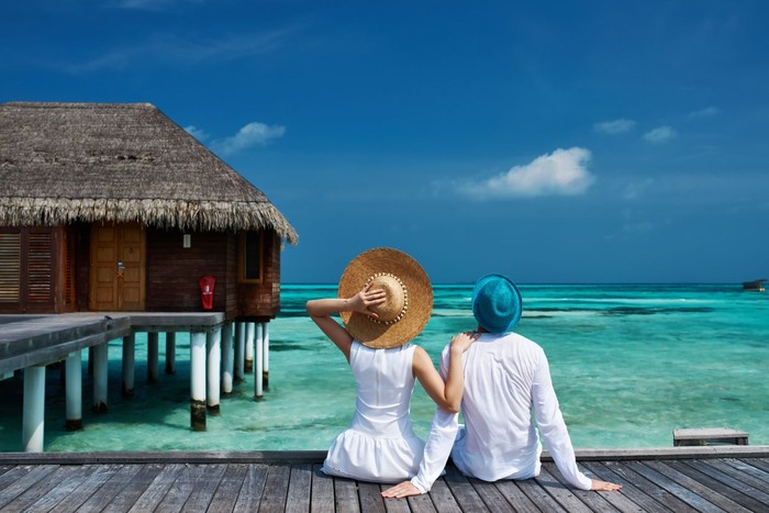 Couple on a tropical beach jetty at Maldives
