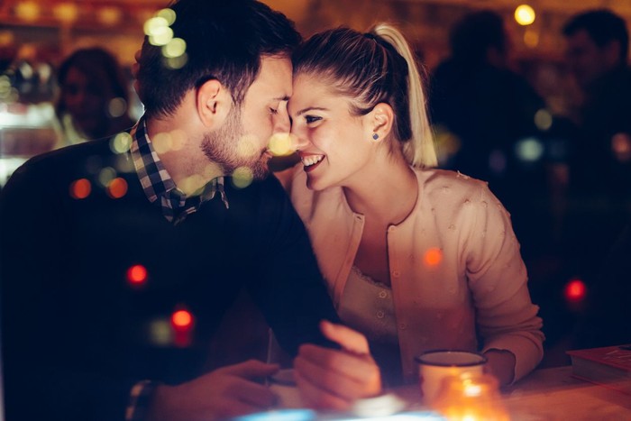 Romantic young couple dating in pub at night