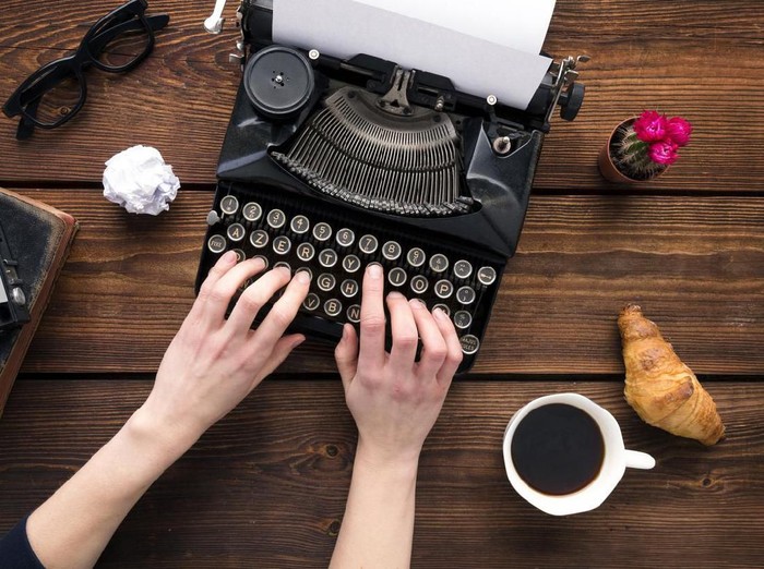Crop person using typewriter