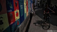 Sejumlah warga melintas di kawasan mural bertemakan pendidikan di kawasan Pademangan Timur, Jakarta Utara, Senin (11/11).