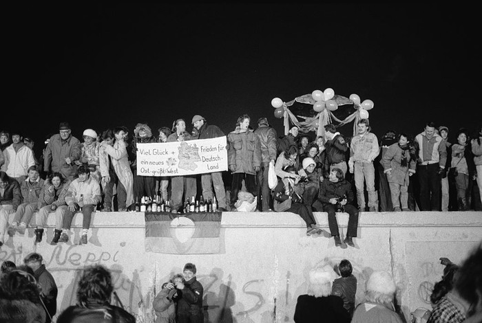 A view from the east of Berliners gathered on the Berlin Wall to celebrate the New Year and the effective end of the citys partition, 31st December 1989. A banner reads Good luck and peace for a new Germany - East Greets West. (Photo by Steve Eason/Hulton Archive/Getty Images)