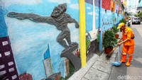 Seorang petugas PPSU tengah membersihkan kawasan Jalan Keamanan III di Taman Sari, Jakarta Barat, yang dinding jalannya nampak tergambar Patung Dirgantara atau dikenal juga dengan nama Patung Pancoran.