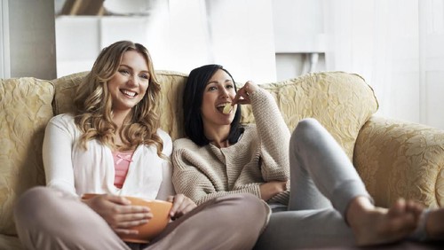 Portrait of a casual woman relaxing at home drinking a cup of coffee and lying on the sofa  - lifestyle concepts