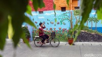 Seorang warga melintasi Jalan Keamanan III di kawasan Taman Sari, Jakarta Barat, yang nampak dihiasi dengan mural 3D, Selasa (12/11/2019).