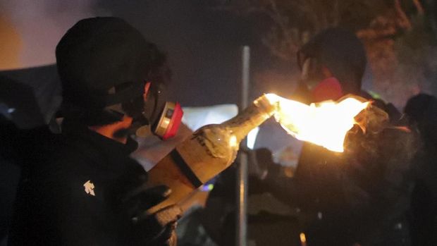 Seorang demonstran Hong Kong memegang bom molotov saat bentrokan dekat kampus setempat