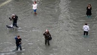Banjir nyatanya tak menyurutkan keriaan turis yang datang berkunjung. Tak sedikit juga yang foto-foto dengan latar banjir (Marco Bertorello/AFP)
