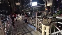 Ada yang datang sendiri, ada juga yang datang bersama teman hingga pasangan. Semuanya ingin melihat pesona malam Jakarta dari atas JPO tanpa atap tersebut (Randy/detikcom)  