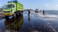 Seorang petugas menyemprotkan air pada jalanan yang berdebu di Pelabuhan PT Citra Nusantara (KCN), Marunda, Jakarta Utara, Jumat (15/11/2019).