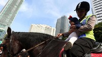 Polisi melayani anak-anak yang ingin menaiki kuda.