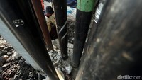 Pekerja nyemplung ke got untuk memperbaiki dinding saluran air.