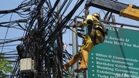 Petugas nampak merapikan kabel semrawut di atas tiang yang berada di kawasan Kemang, Jakarta.