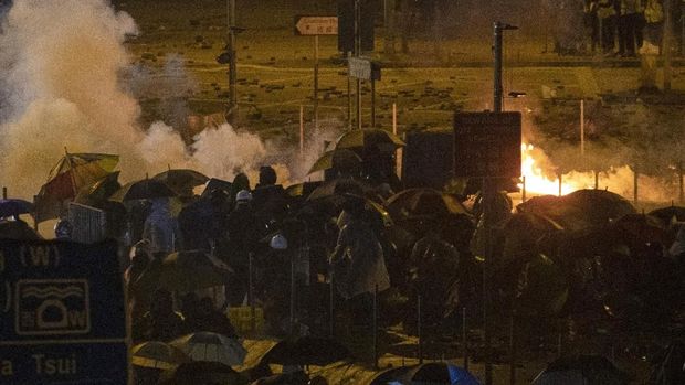 Demonstran Hong Kong berlindung dari gas air mata yang ditembakkan polisi