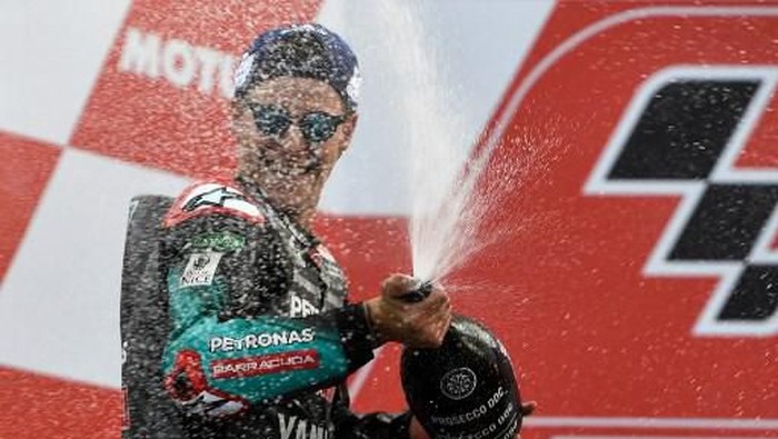 Second placed Petronas Yamaha SRTs French rider Fabio Quartararo (R) celebrates with champagne on the podium after the MotoGP race of the MotoGP Valencia Grand Prix at the Ricardo Tormo racetrack in Cheste near Valencia, on November 17, 2019. (Photo by PIERRE-PHILIPPE MARCOU / AFP)