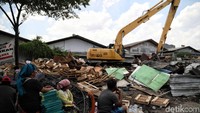 Warga tetap bertahan di tengah deru mesin ekskavator yang melakukan pembongkaran bangunan.