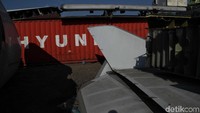 puing-puing pesawat tersebut dikelilingi sejumlah kontainer.