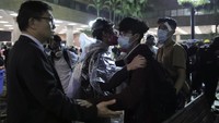 Salah seorang demonstran pelajar meninggalkan kawasan kampus didampingi kelapa sekolahnya. Kin Cheung/AP Photo.