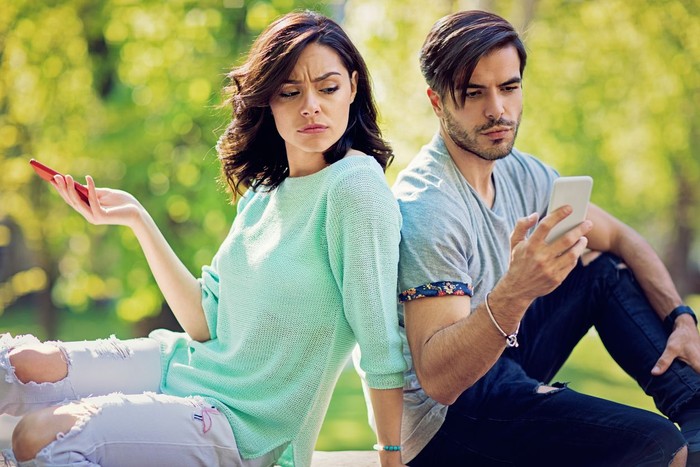 zodiak Couple in conflict is texting in the park and sulking each other