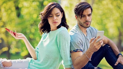 Couple in conflict is texting in the park and sulking each other