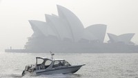 Sebuah perahu melintas di area sekitar Sydney Opera House yang diselimuti kabut asap. Rick Rycroft/AP Photo.