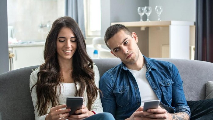 Couple in conflict is texting in the park and sulking each other