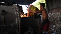 Seorang pekerja di pabrik tahu yang berada di Desa Tropodo, Sidoarjo, sedang menambahkan sampah plastik ke tungku pembakaran untuk digunakan sebagai bahan bakar pembuatan tahu.