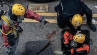 Petugas pemadam kebakaran nampak mencoba memasuki selokan bawah tanah untuk mencari para demonstran yang mencoba melarikan diri kampus PolyU Hong Kong melalui jalur tersebut. Anthony Kwan/Getty Images.