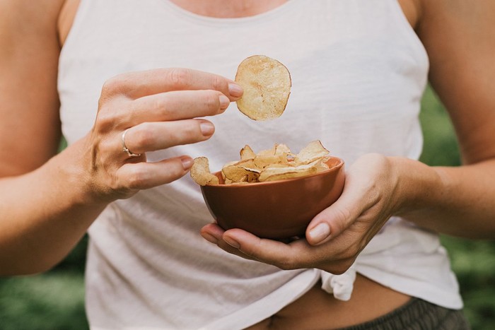 Woman eating chips snacks, close up of hands
Photo taken in summer in sunlight outdoors