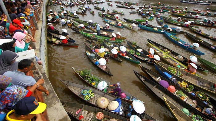 Sejumlah pedagang pasar terapung membagikan sayur dan buah di sungai Martapura, Banjarmasin, Kalimantan Selatan, Minggu (24/11/2019). Sebanyak 374 pedagang pasar terapung berhasil memecahkan Rekor Museum Indonesia (MURI) sebagai rekor pembagian sayuran dan buah dari jukung terbanyak. ANTARA FOTO/Bayu Pratama S/aww.