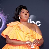 Pelantun Truth Hurts itu muncul dalam balutan gaun mini Valentino dengan garis leher asimetris. Gaun oranye tersebut hadir dengan gaya ruffle bertumpuk.  (Foto: Getty Images)